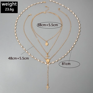 Detail of layered gold metal chains with pearls, religious cross, and Virgin Mary pendants