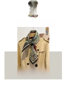 Detail of leaf print cotton linen small square scarf styled on a beige trench coat