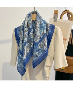 Close-up of blue paisley silk scarf draped over a beige puff-sleeve garment for styling