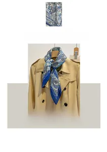 Detailed blue paisley pattern on soft cotton linen scarf styled with a khaki trench coat