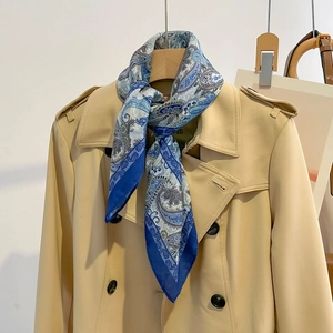 Blue paisley cotton linen feel scarf tied on a beige trench coat for a stylish look