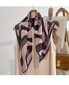 Detailed view of camellia silk scarf with rose patterns draped on a beige blouse