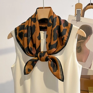 Elegante zijden sjaal met luipaardprint aan houten hanger bij een witte mouwloze jurk