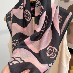 Elegant black and pink silk scarf with camellia patterns styled on a white top