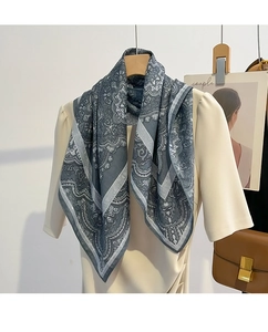 Détail d'un foulard en coton gris à motif paisley porté sur un haut blanc élégant