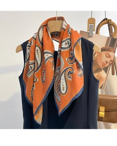 Close-up of an orange paisley cotton scarf styled over a black shirt with magazines
