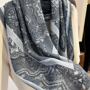 Gros plan du foulard à motif cachemire bleu et gris sur un vêtement de couleur beige