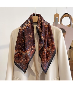 Detail of silk-textured square scarf with kaleidoscope pattern on a beige suit lapel