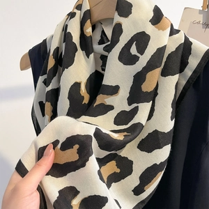 Modieuze lichte zijden sjaal met luipaardprint gedrapeerd over een houten kledinghanger