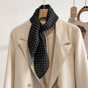 Elegant white polka dot silk scarf on beige blazer with minimalist office aesthetic