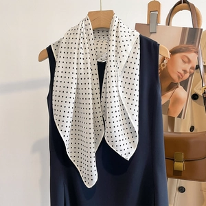 Elegant white polka dot silk scarf for women hanging on a wooden hanger with dress