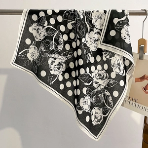 Close-up of elegant black and white polka dot silk scarf with floral pattern on rack