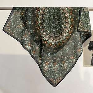 Macro detail of high-quality square silk scarf featuring complex green mandala pattern