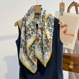 Floral silk scarf with red flower print and yellow border styled on a dark blue top