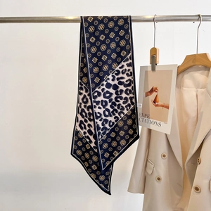 Détail d'un foulard en soie avec motif floral marine et imprimé léopard sur un support