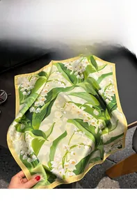 Détail d'un foulard en soie avec motifs floraux de muguet vintage et bord jaune