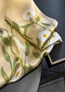 Close-up of fine stitched edges on a champagne silk scarf with daisy floral print