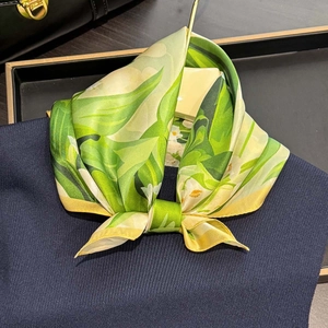 Foulard en soie à imprimé lys vert et jaune suspendu sur un cintre doré élégant