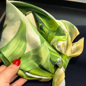 Détail d'un foulard en soie avec imprimé floral vert et texture satinée lisse et brillante