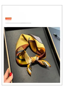 Macro view of geometric silk square scarf featuring yellow and brown color blocking
