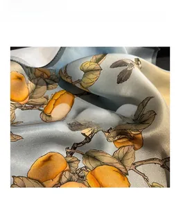 Detail of premium light blue silk scarf featuring bird and persimmon floral patterns