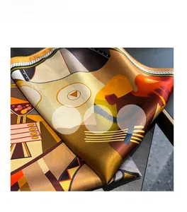 Macro detail of silk-like geometric print scarf showing orange patterns and rolled edges