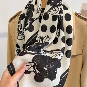 White silk scarf with black floral polka dots and herringbone texture on beige coat