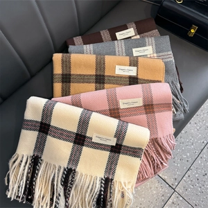 Detailed display of assorted plaid scarves with fringe in beige, pink, and grey