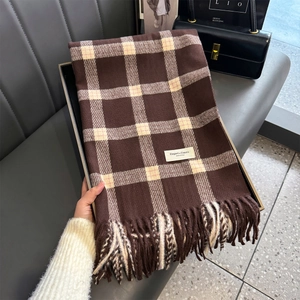 Detail of classic plaid scarf featuring soft fringe and elegant branding label