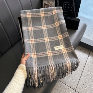 Detail shot of grey plaid scarf featuring soft thick fabric and elegant fringe tassels
