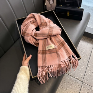 Close-up of pink plaid tassel scarf with Elegant & Classic tag on a black tray