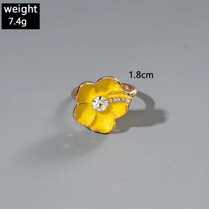 Vista macro di un anello a fiore di camelia in smalto giallo con strass e misure
