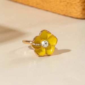 Dettaglio di un anello a fiore in smalto giallo con cristalli scintillanti su oro