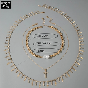 Detailed view of multilayer gold necklace set with cross pendants and imitation pearls