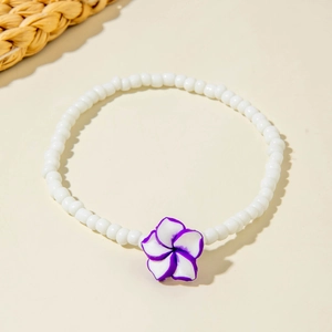 Detail of white beaded anklet featuring a resin frangipani flower for bohemian style