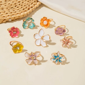 Set di nove anelli floreali barocchi colorati con perle su uno sfondo estivo naturale