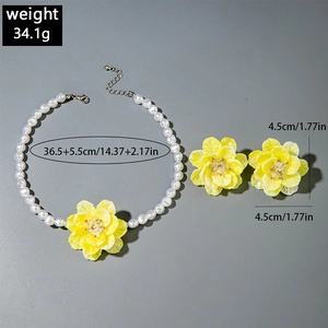 Detailed view of yellow floral pendant necklace and earrings set with pearl beads