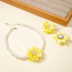 Detail of sweet floral jewelry set with yellow petals, pearl necklace and stud earrings