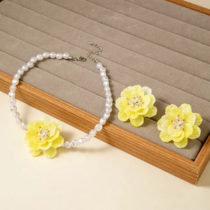 Detail of yellow flower jewelry set with white pearls on a velvet tray display