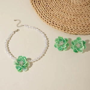 Detailed shot of green floral jewelry set with resin petals and white pearl necklace