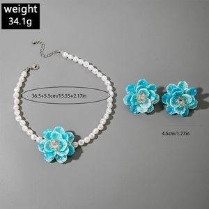 Detail showing blue resin flower necklace and matching earrings set with white pearls