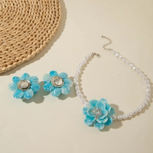 Close-up of pearl necklace and blue floral earrings on a summer aesthetic straw mat