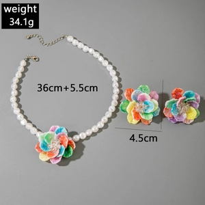 Detail of colorful flower jewelry set with pearl necklace and matching stud earrings