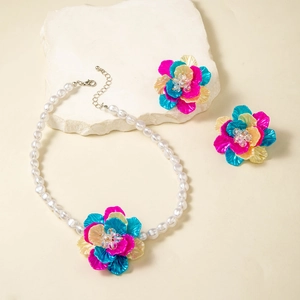 Macro detail of multi-layered floral pendant and matching earrings with white resin pearls