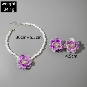 Detail view of purple floral jewelry set with pearl necklace and large petal earrings