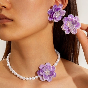 Detail of purple flower jewelry set with pearl necklace and matching stud earrings
