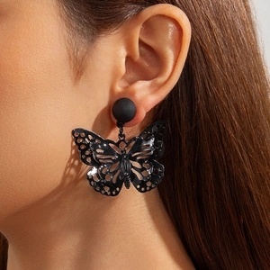 Close-up of black hollow butterfly stud earrings showing intricate wing mesh and size on ear