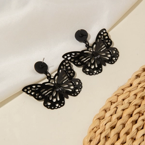 Gothic butterfly stud earrings with hollow wings on white silk and textured fabric background
