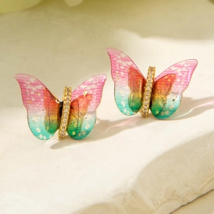 Macro shot of colorful gradient butterfly earrings with sparkling stones on marble base