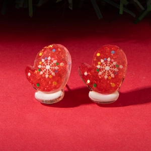 Macro detail of red Christmas glove earrings with glitter finish and snowflake patterns